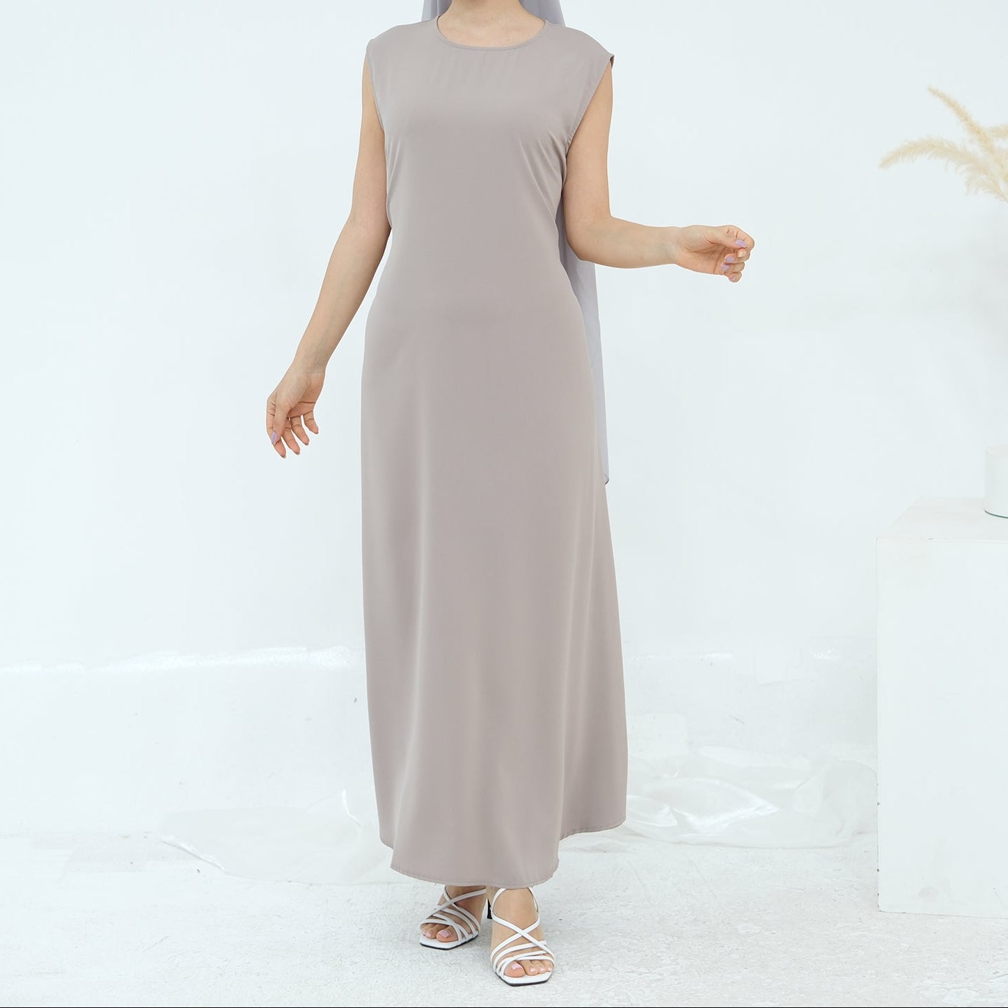 Woman wearing a long beige dress on a white background