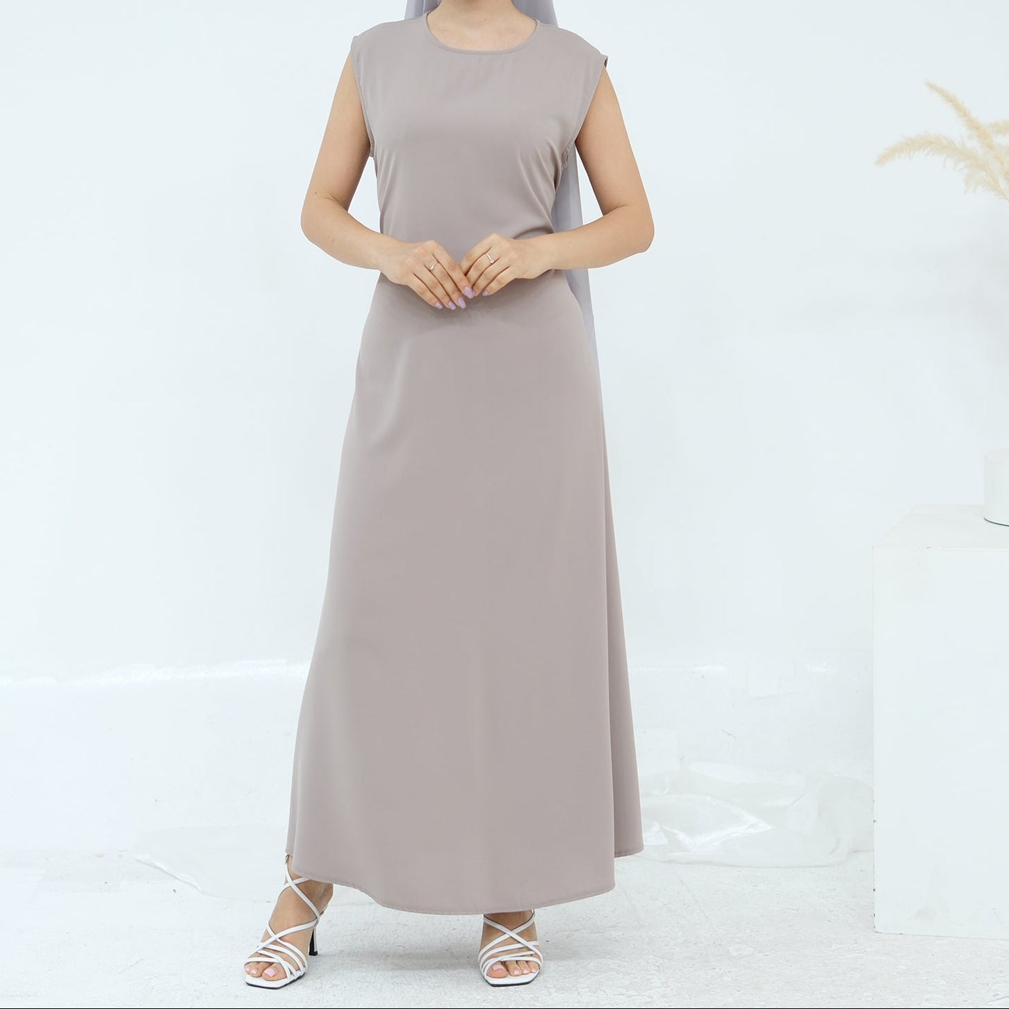 Woman wearing a long beige dress on a white background