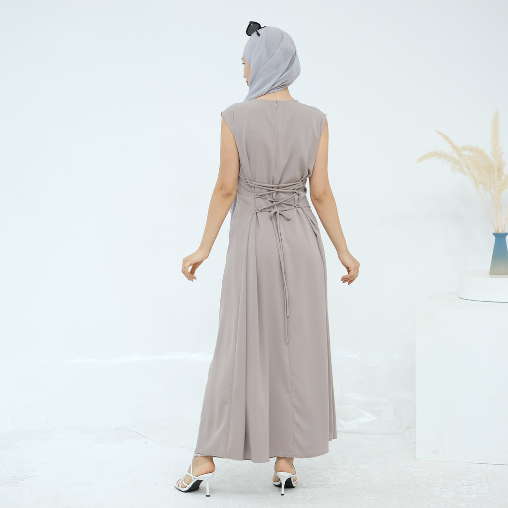 Woman wearing a long beige dress with a belt on a white background