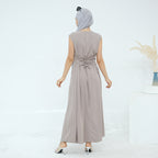 Woman wearing a long beige dress with a belt on a white background