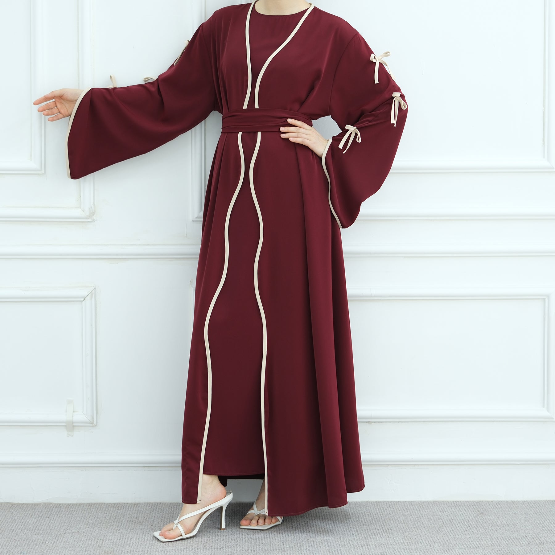 Maroon dress with white trim worn by a person against a white paneled wall.