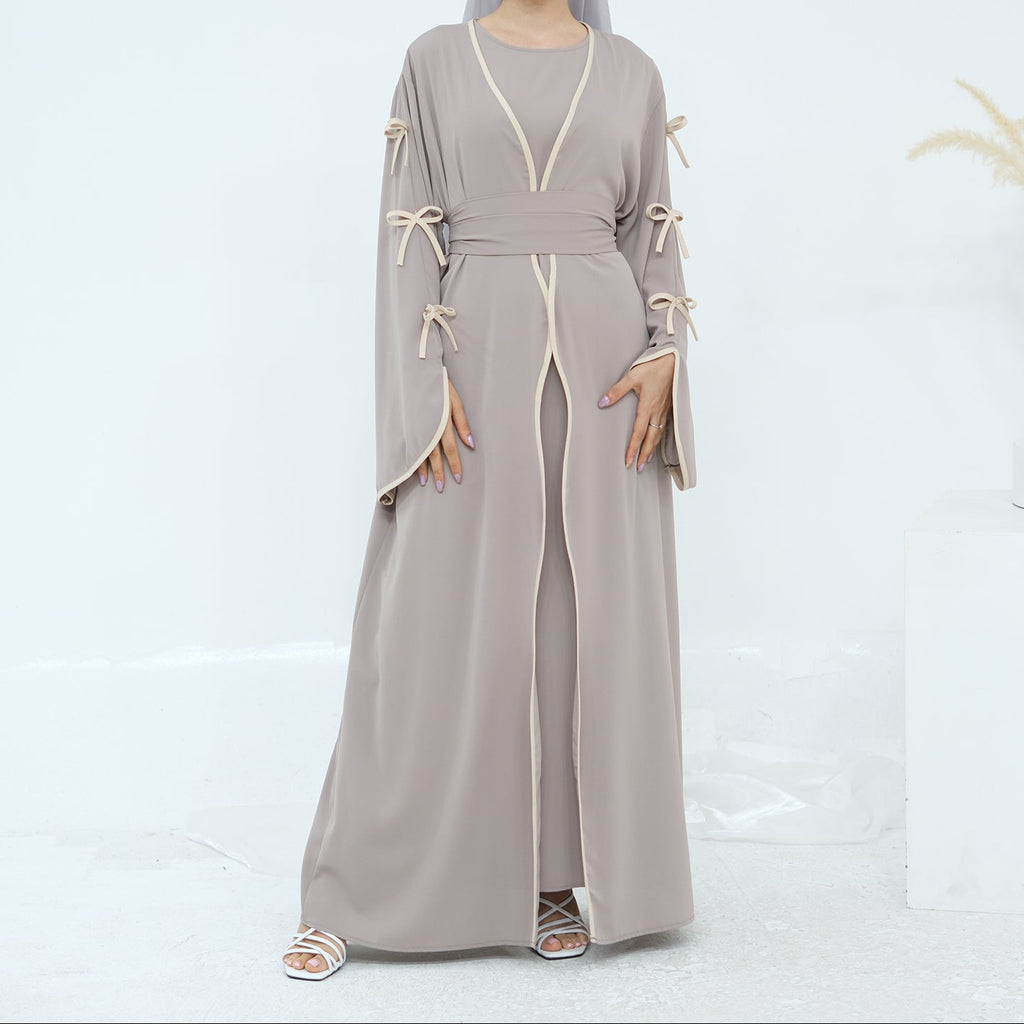 Woman wearing a long, light gray dress with decorative elements on a white background