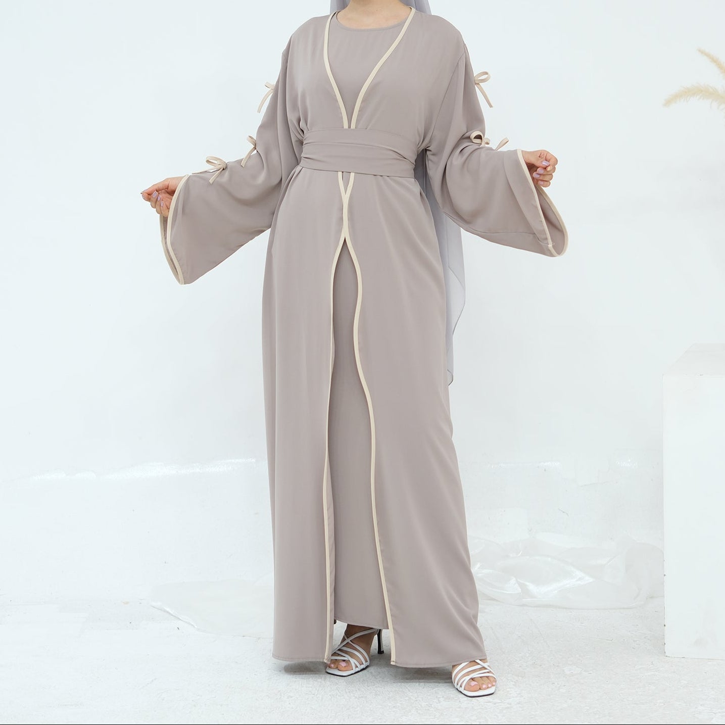 Woman wearing a long, light gray dress with a white background