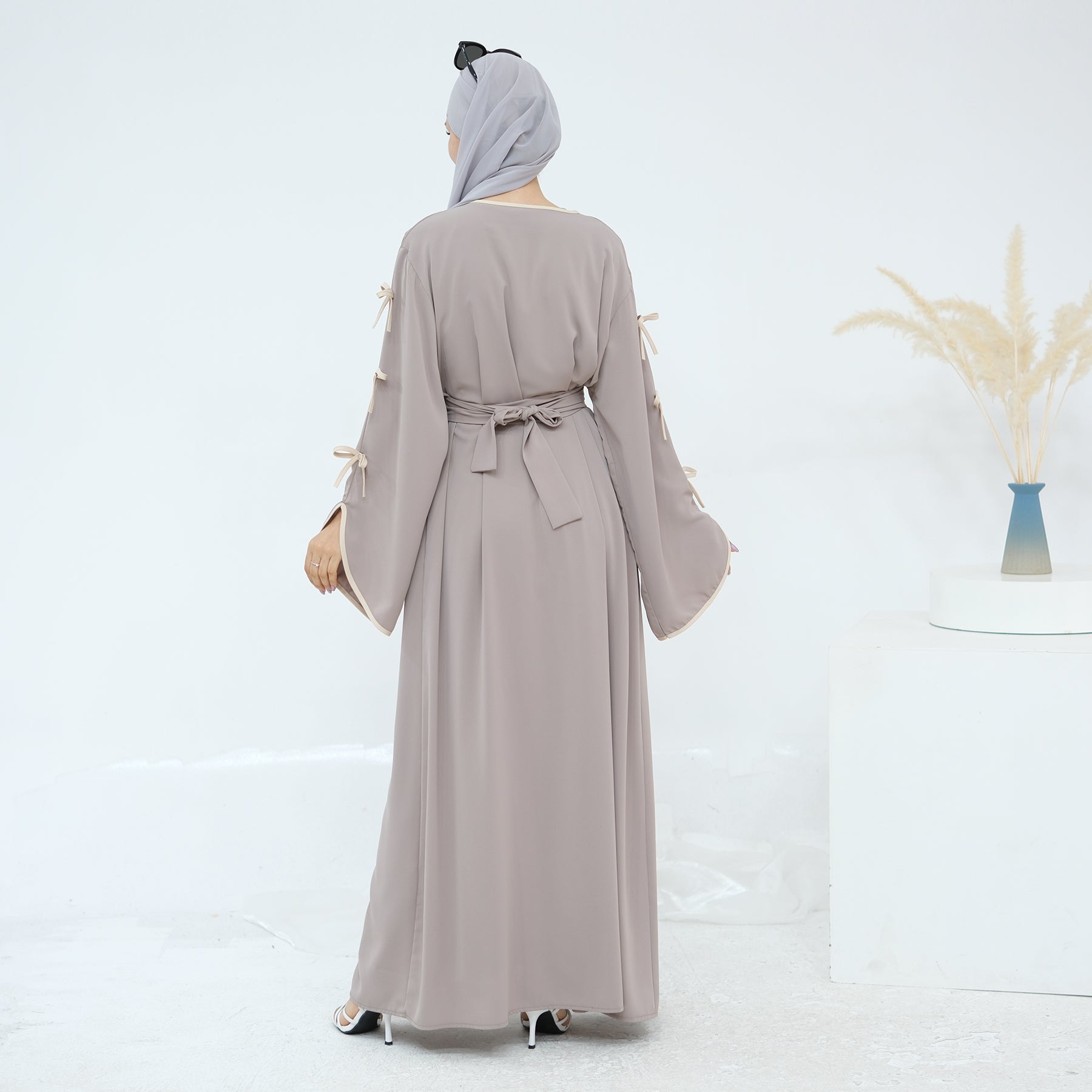 Woman wearing a long beige dress with a belt on a white background