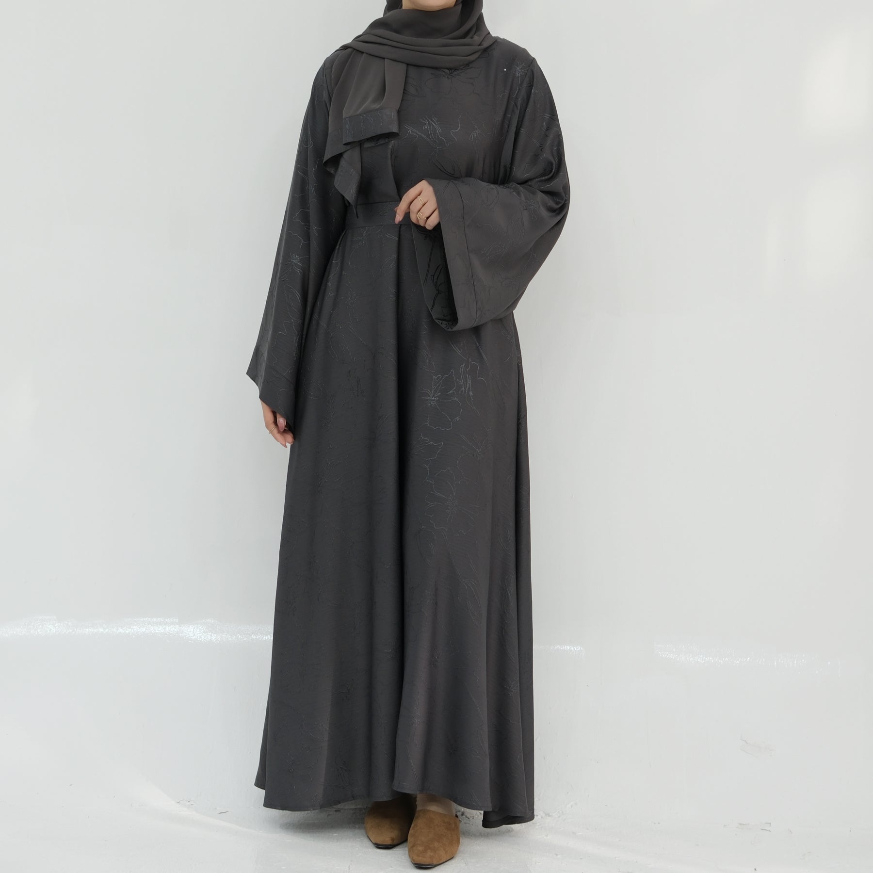 Person wearing a long dark gray dress against a white background