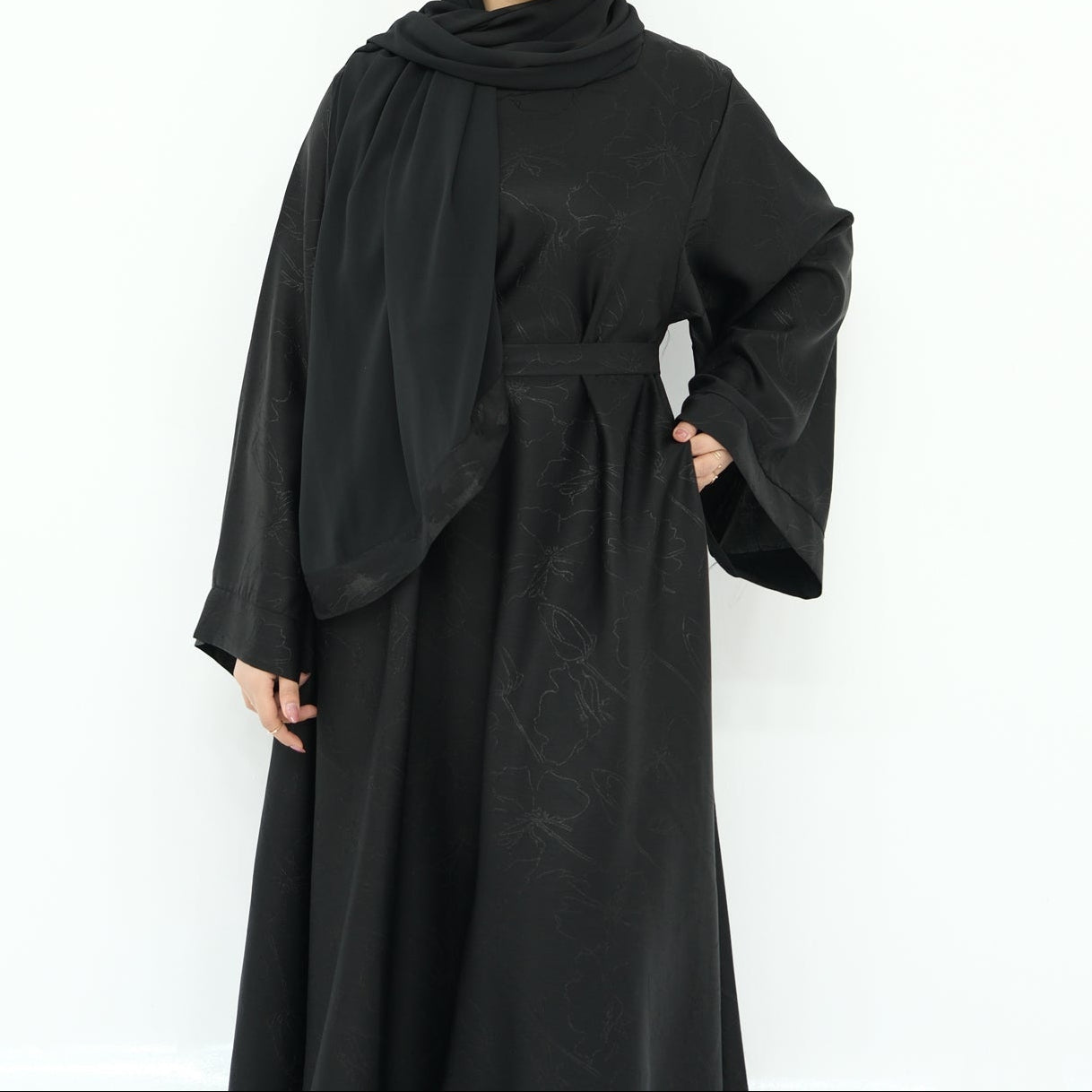 Woman wearing a black abaya and hijab on a white background