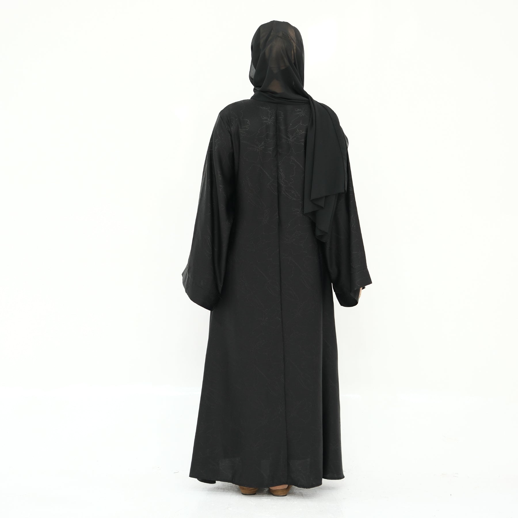 Black abaya worn by a person on a white background