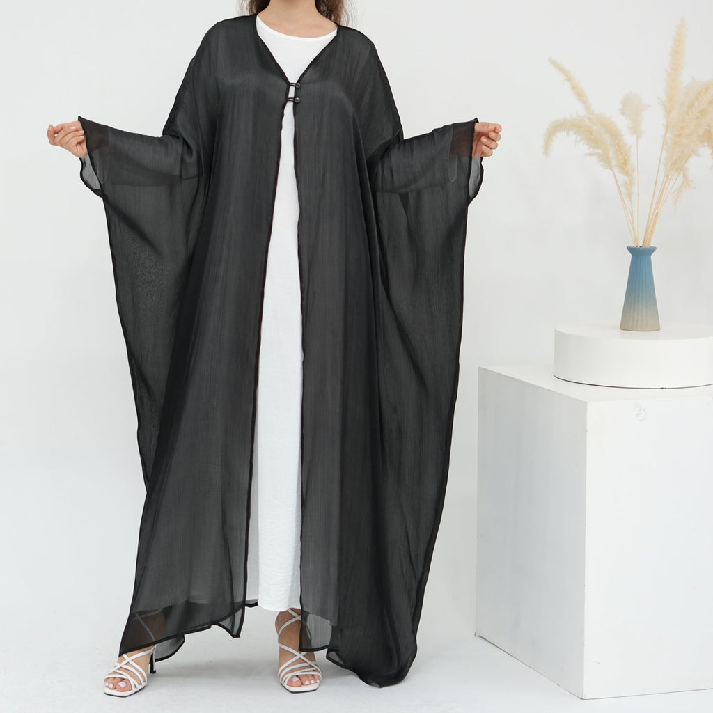 Woman wearing a black abaya over a white dress on a white background LayalAl-FajrAbaya_Noor_GraceBlack1