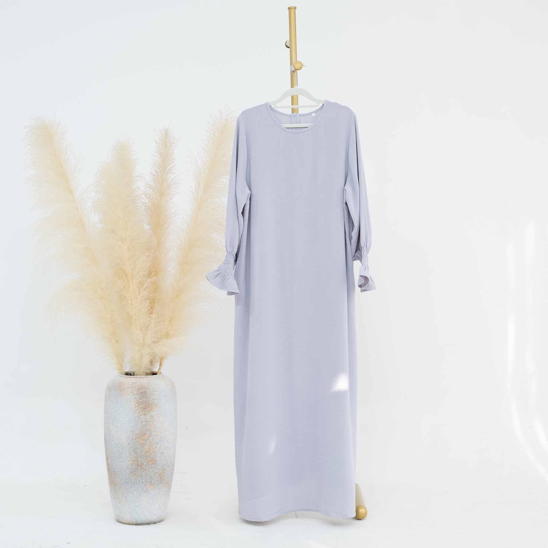 Light purple dress on a hanger with decorative elements on a white background