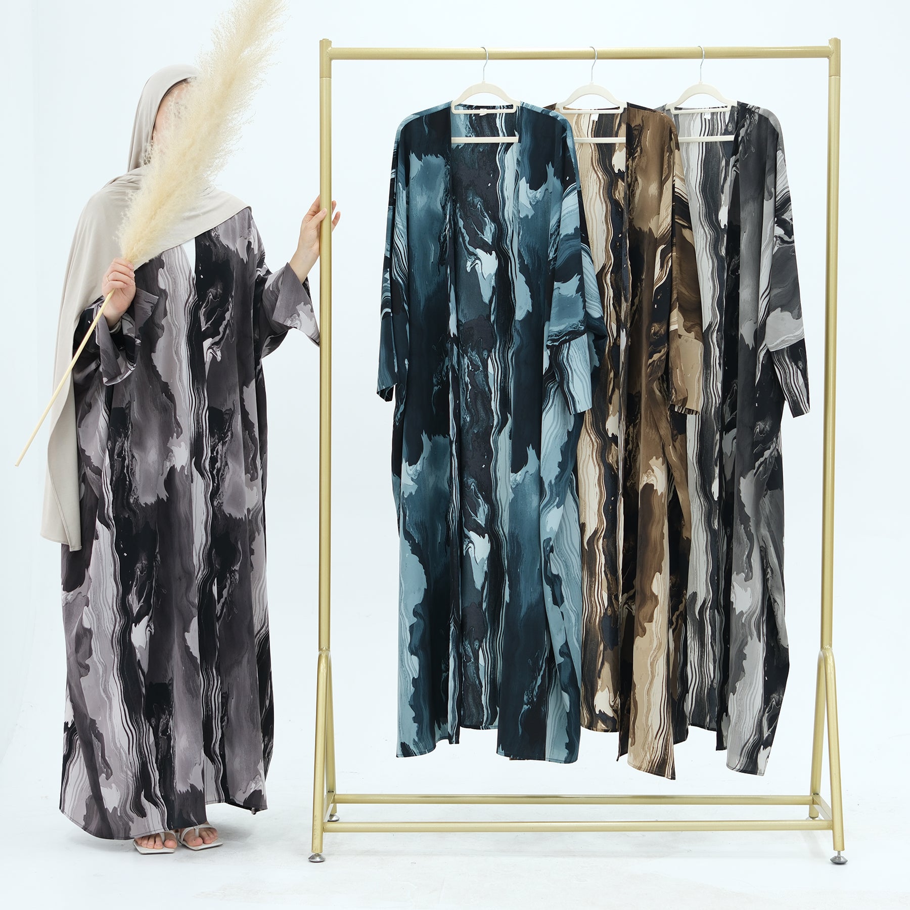 Marbled patterned dresses on a gold clothing rack against a white background