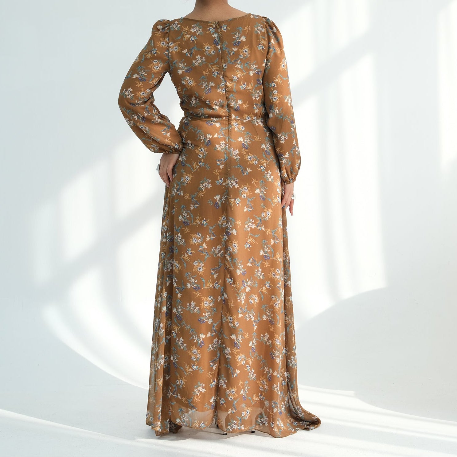 Woman wearing a long floral dress in a white studio setting