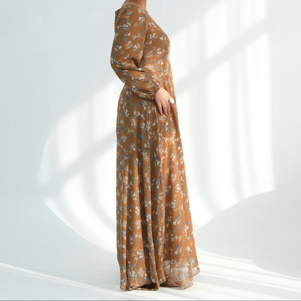 Woman wearing a long, patterned dress against a white background