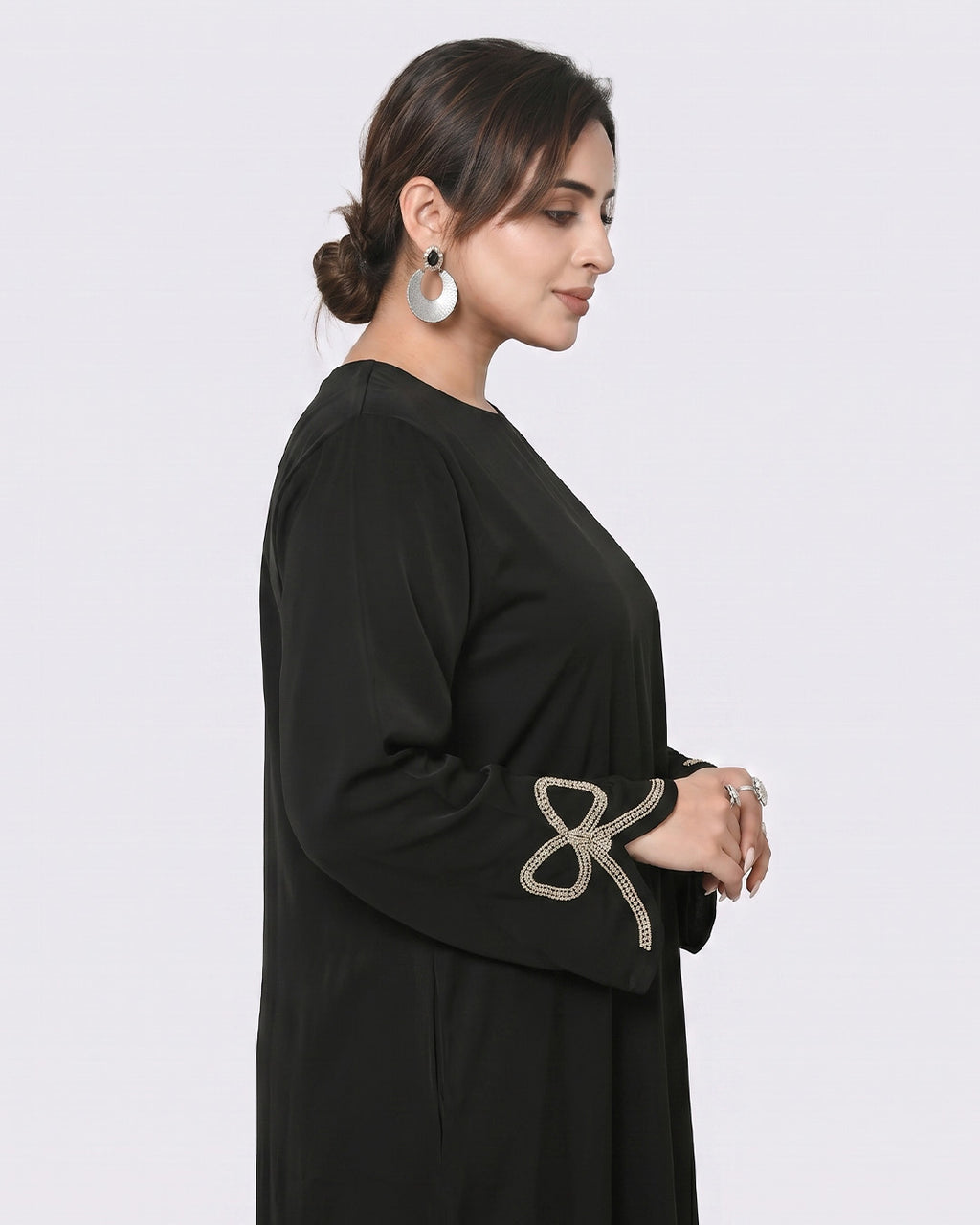 Woman wearing a black abaya with decorative sleeves on a white background