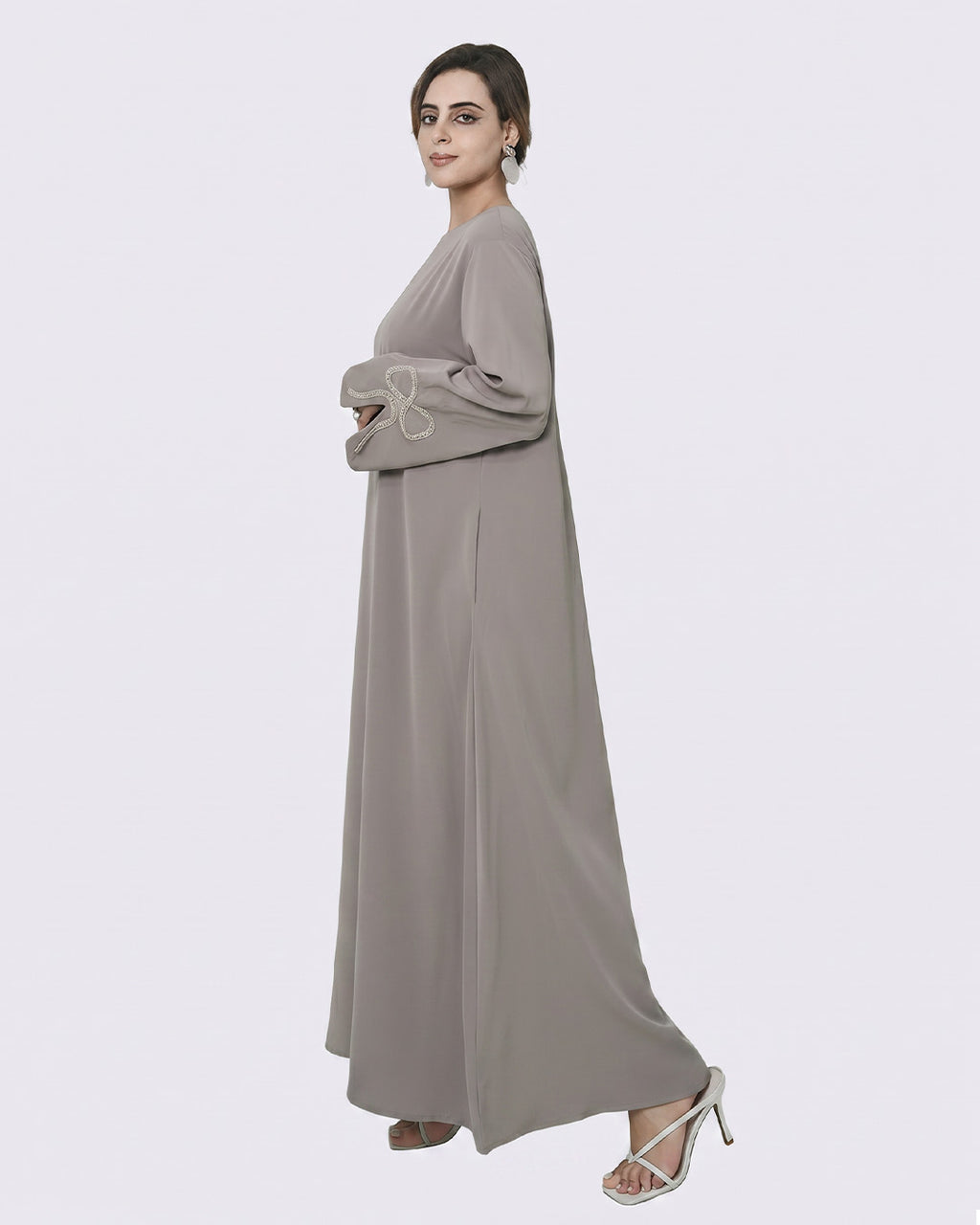 Woman wearing a long, light gray dress on a white background