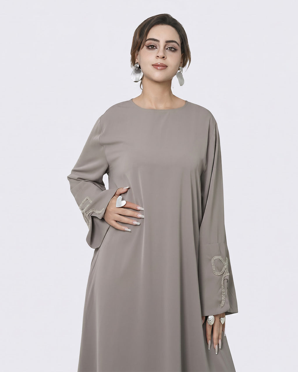Woman wearing a gray dress with long sleeves on a white background