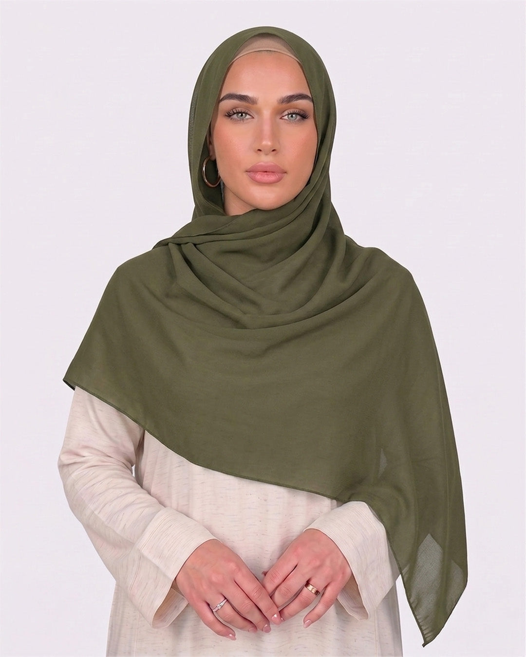 Model wearing a lightweight, army green chiffon hijab wrapped elegantly over a beige long-sleeved dress.