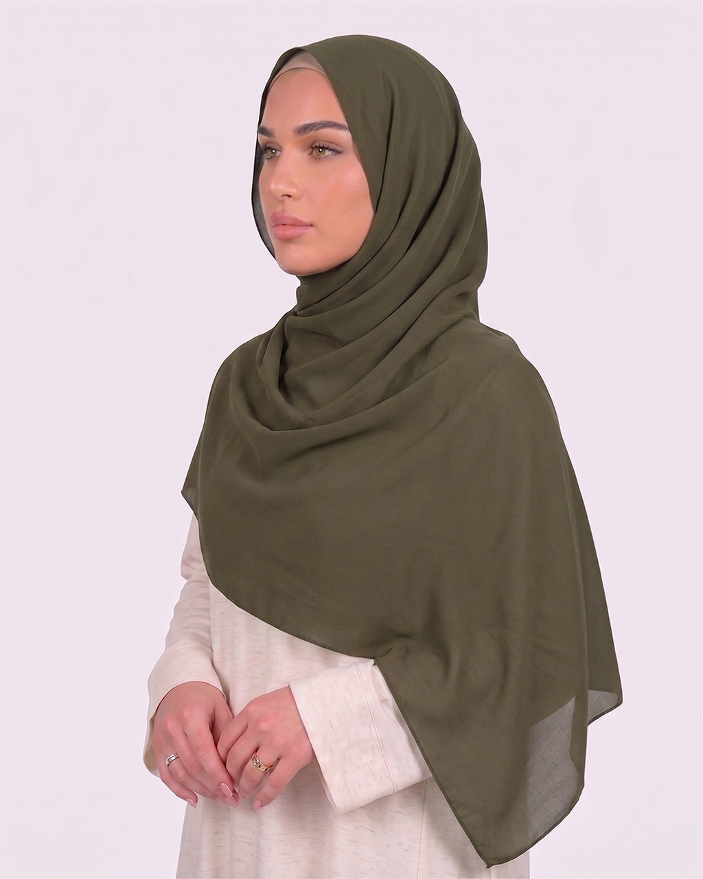 Model wearing a lightweight, army green chiffon hijab wrapped elegantly over a beige long-sleeved dress.