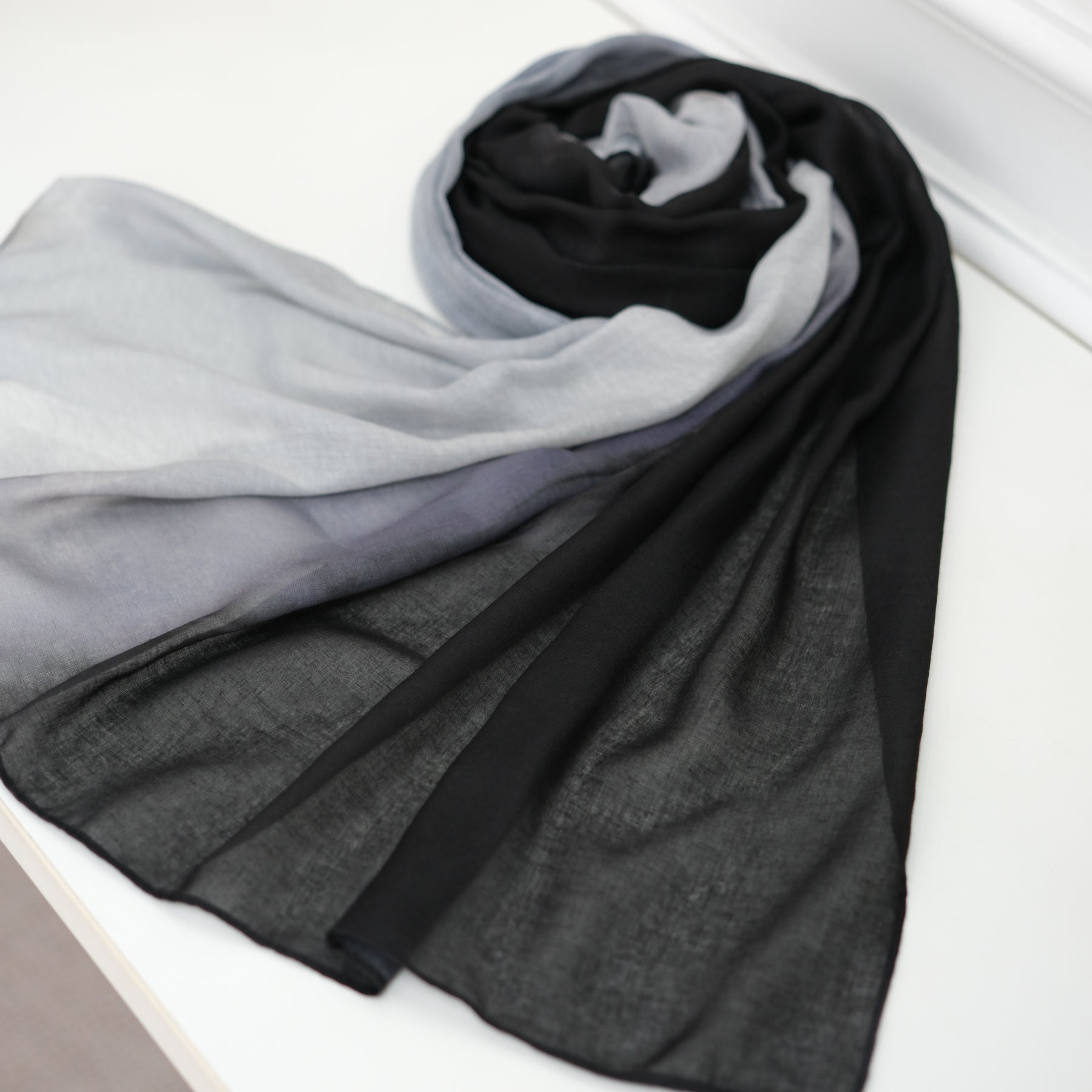 Gradient scarf in gray, black, and white on a white surface
