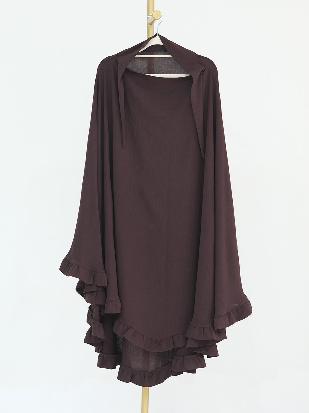 A dark brown draped tunic top with wide sleeves and layered ruffles along the hem, hanging on a wooden hanger against a plain white background.