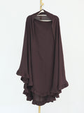 A dark brown draped tunic top with wide sleeves and layered ruffles along the hem, hanging on a wooden hanger against a plain white background.