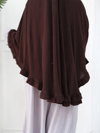 A dark brown sheer chiffon shawl or wrap with ruffled edges, worn over white trousers.