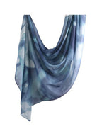 A lightweight, semi-sheer scarf with a blue and gray watercolor or tie-dye pattern, draped against a solid white background.