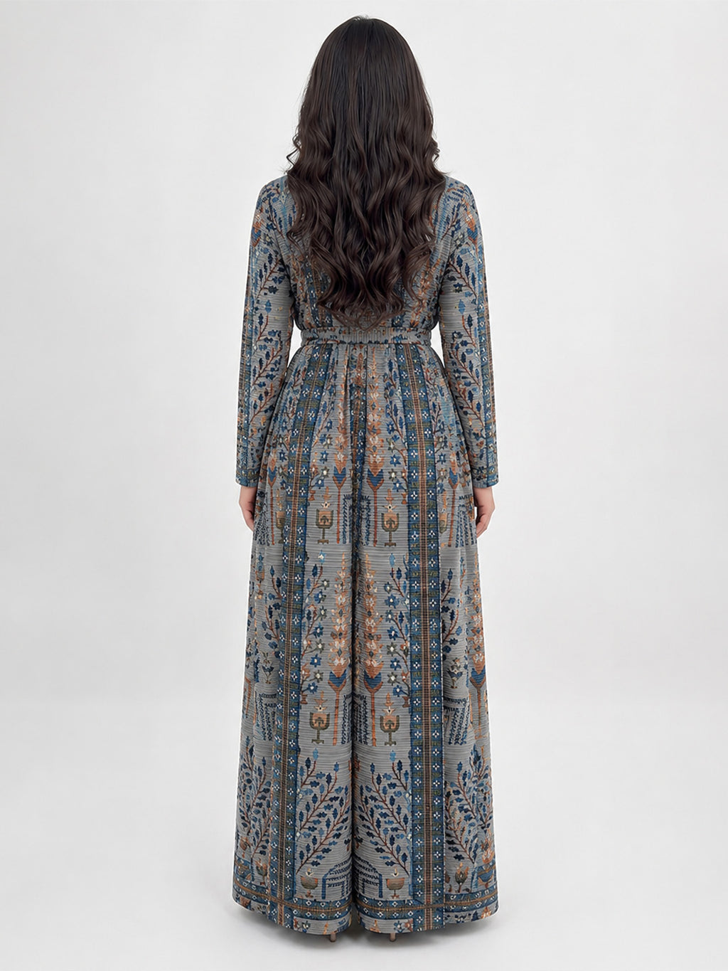 A woman viewed from the back wearing a long-sleeved maxi dress with an intricate blue, gray, and beige patterned print, set against a plain light gray studio background.