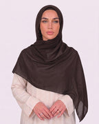 Model wearing a lightweight, espresso chiffon hijab wrapped elegantly over a beige long-sleeved dress.