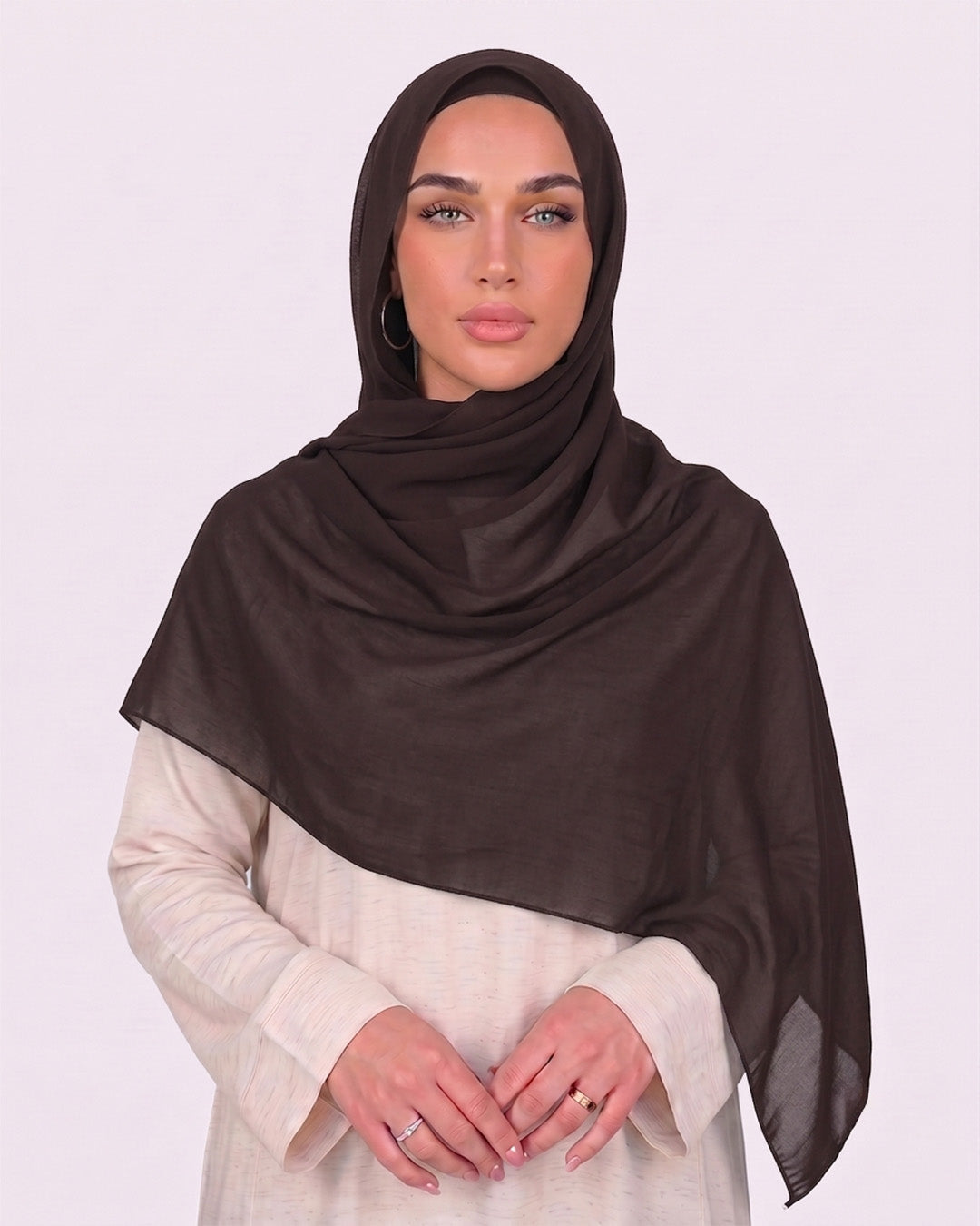 Model wearing a lightweight, espresso chiffon hijab wrapped elegantly over a beige long-sleeved dress.