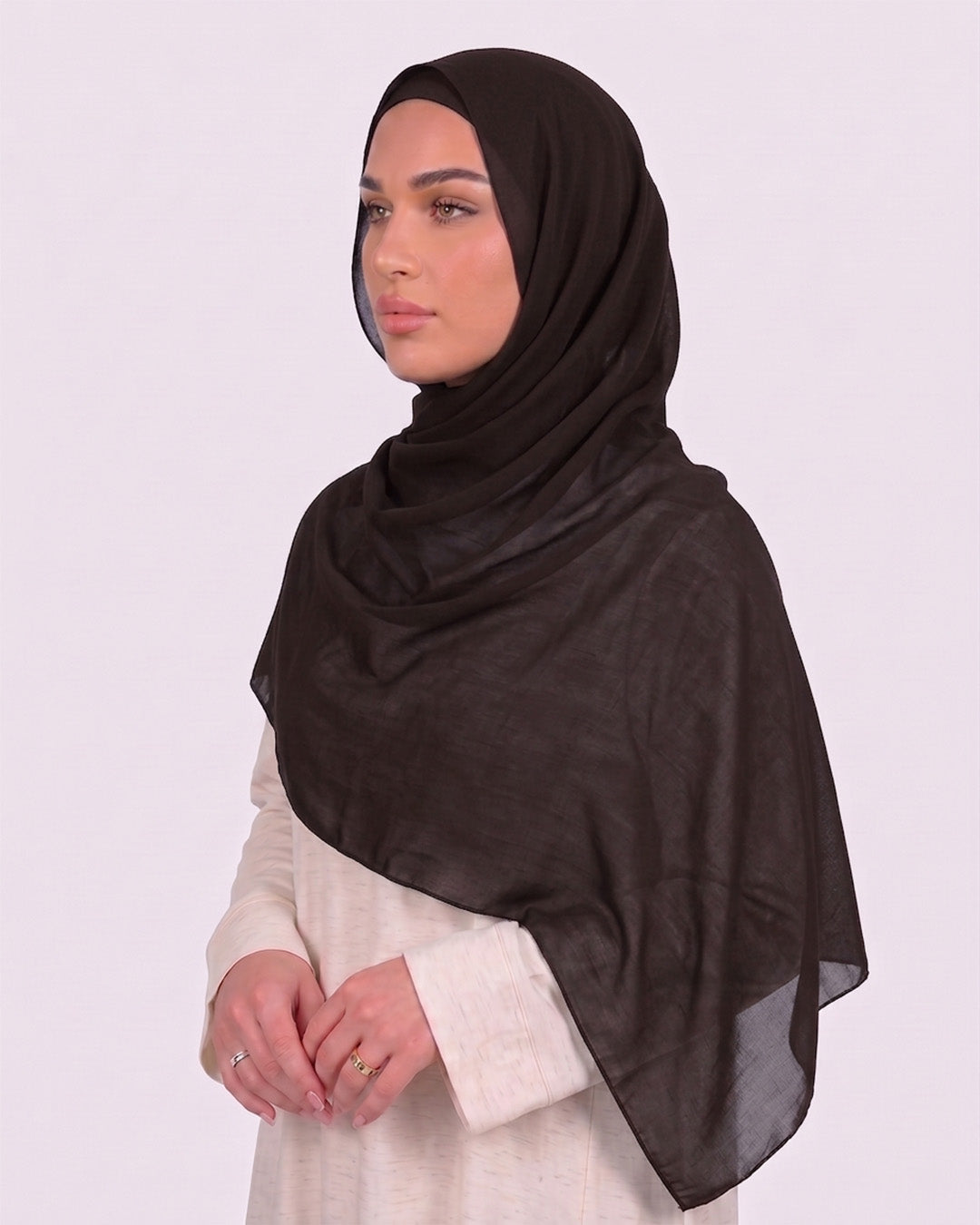 Model wearing a lightweight, espresso chiffon hijab wrapped elegantly over a beige long-sleeved dress.