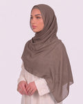 Model wearing a lightweight, latte chiffon hijab wrapped elegantly over a beige long-sleeved dress.