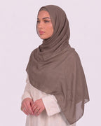 Model wearing a lightweight, latte chiffon hijab wrapped elegantly over a beige long-sleeved dress.