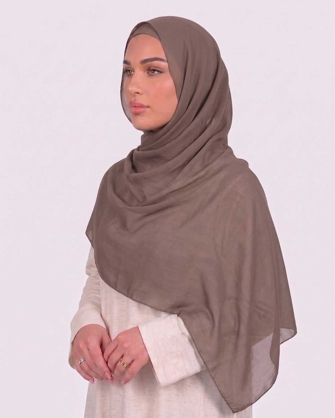 Model wearing a lightweight, latte chiffon hijab wrapped elegantly over a beige long-sleeved dress.