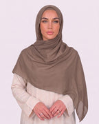 Model wearing a lightweight, latte chiffon hijab wrapped elegantly over a beige long-sleeved dress.