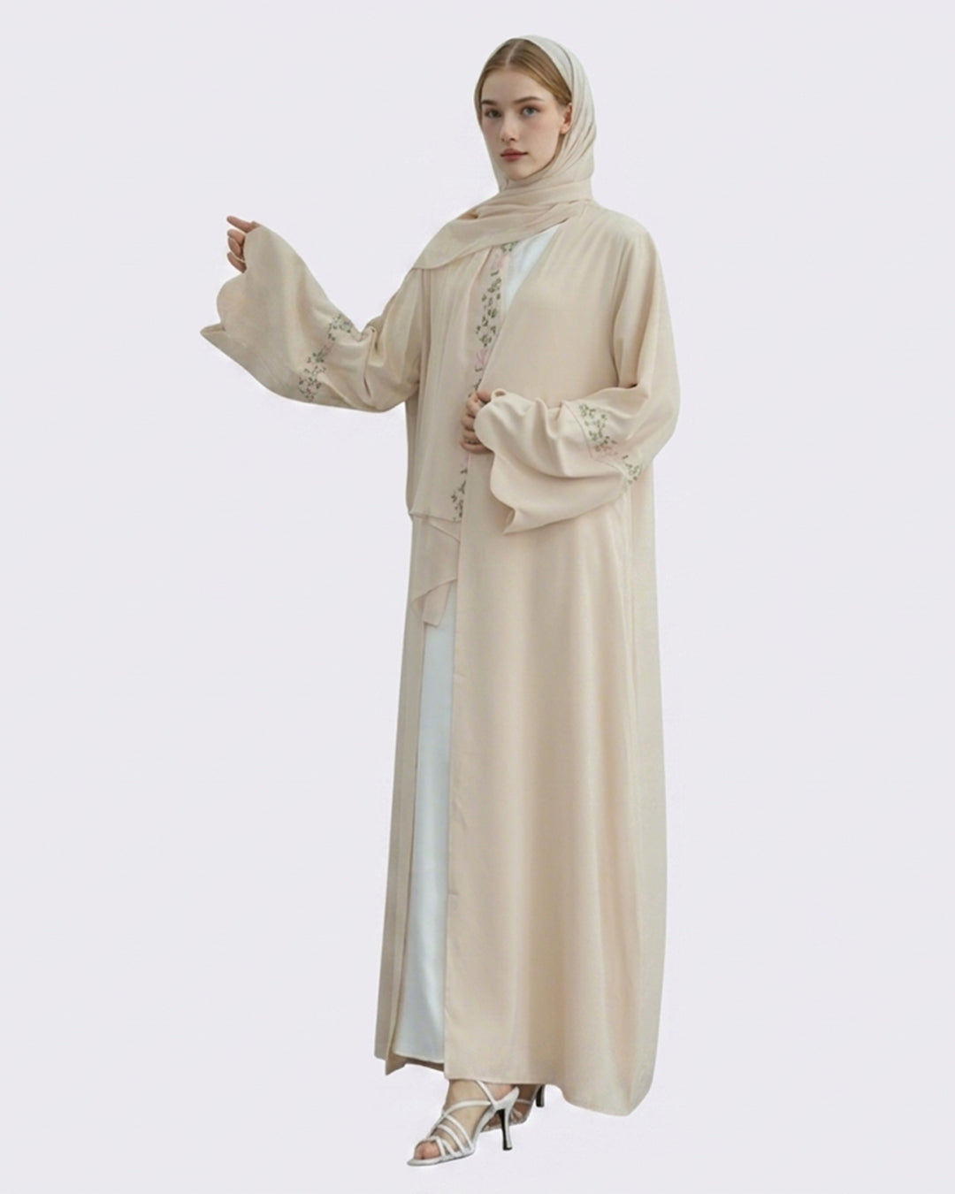 Woman wearing a beige abaya with intricate designs on a white background