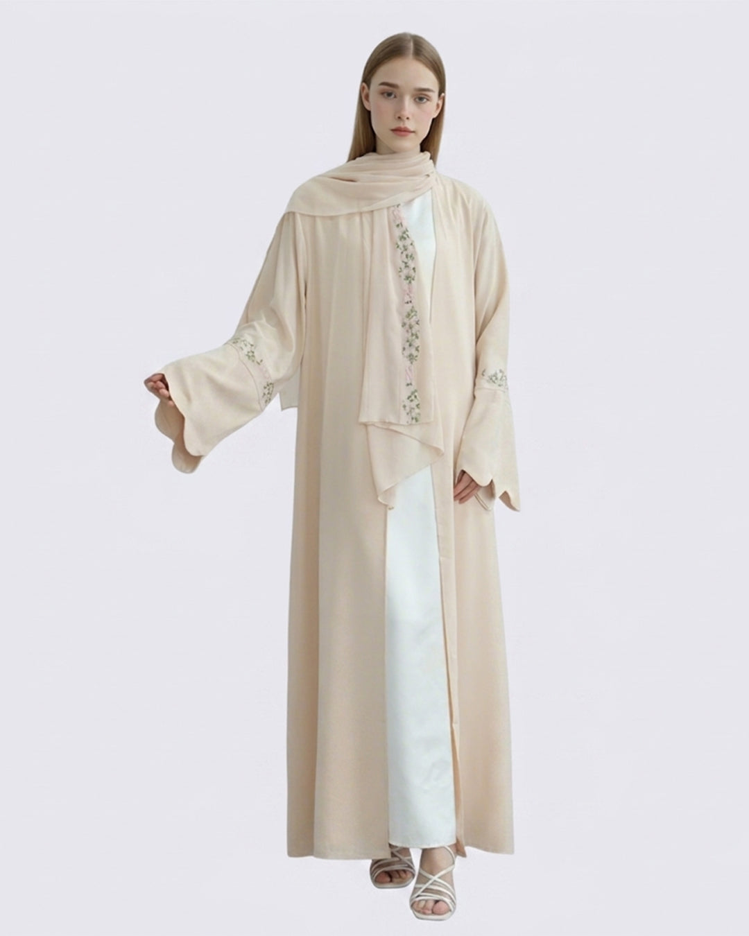 Woman wearing a beige long garment with lace details on a light gray background