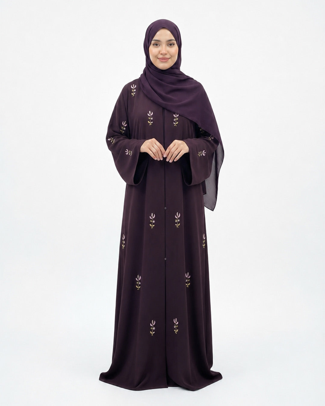 Woman wearing a dark purple abaya with floral embroidery on a white background