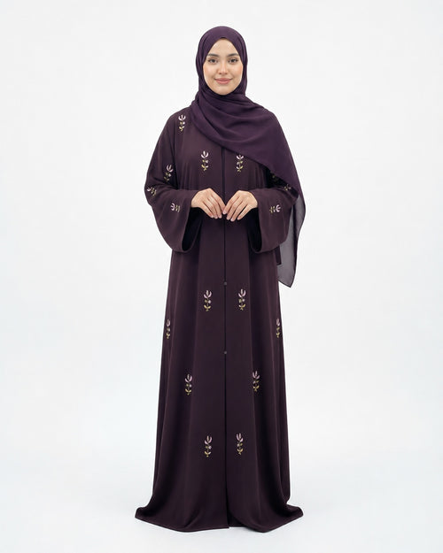 Woman wearing a dark purple abaya with floral embroidery on a white background