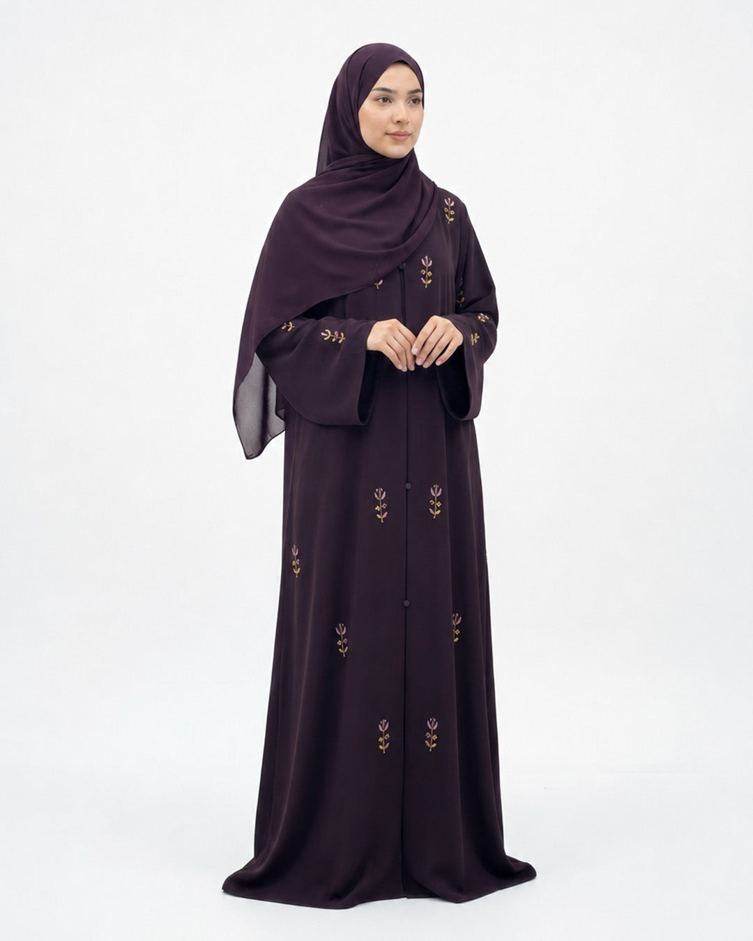 Woman wearing a dark purple abaya with floral embroidery on a white background