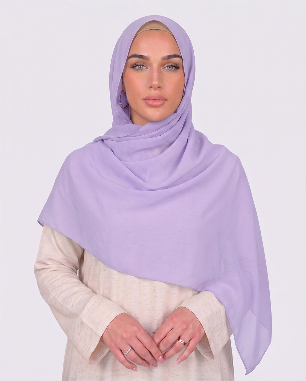 Model wearing a lightweight, light purple chiffon hijab wrapped elegantly over a beige long-sleeved dress.