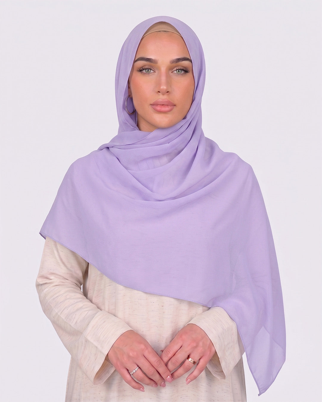 Model wearing a lightweight, light purple chiffon hijab wrapped elegantly over a beige long-sleeved dress.
