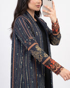 A woman takes a mirror selfie wearing a dark navy open-front cardigan with vertical stripes and ornate gold and red patterned sleeves, layered over a black top.
