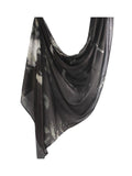 A lightweight black scarf with a gray and white abstract watercolor pattern, draped elegantly against a plain white background.