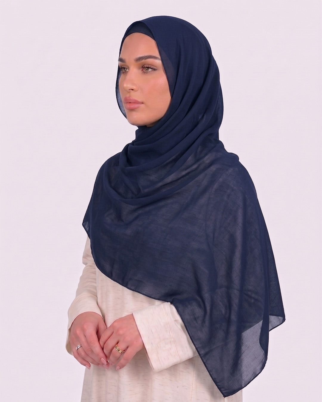 Model wearing a lightweight, navy blue chiffon hijab wrapped elegantly over a beige long-sleeved dress.