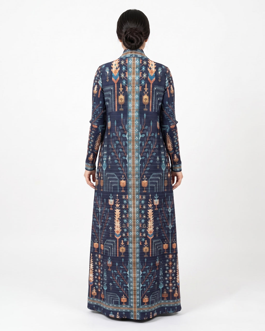 A woman viewed from the back wearing a long-sleeved navy blue maxi dress with an intricate geometric and tribal pattern in beige, orange, and light blue, set against a plain white studio background.