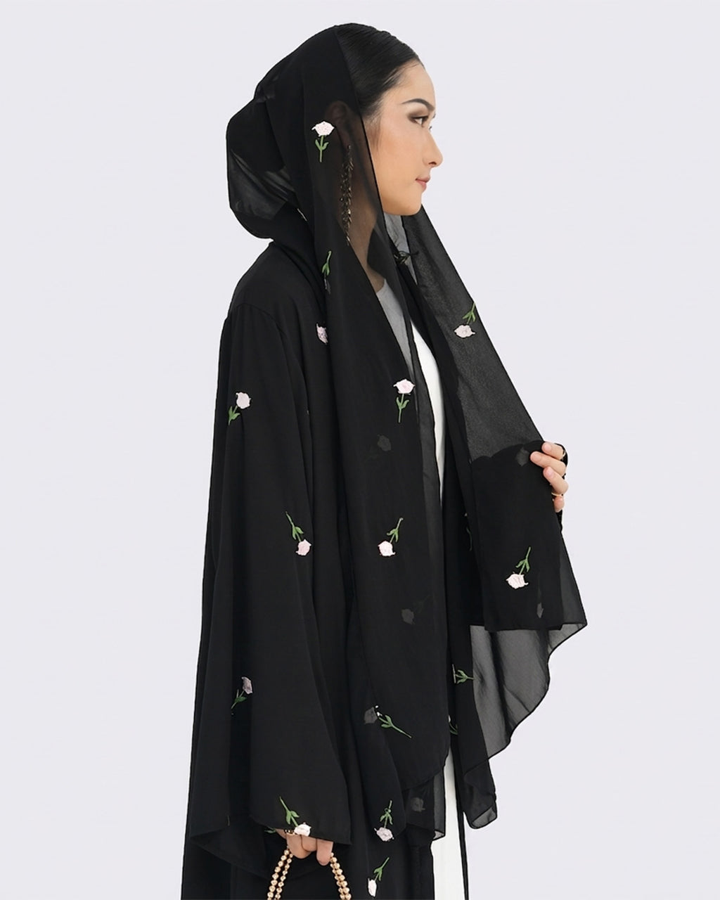 Woman wearing a black hijab with floral embroidery on a white background