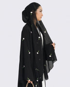 Woman wearing a black hijab with floral embroidery on a white background