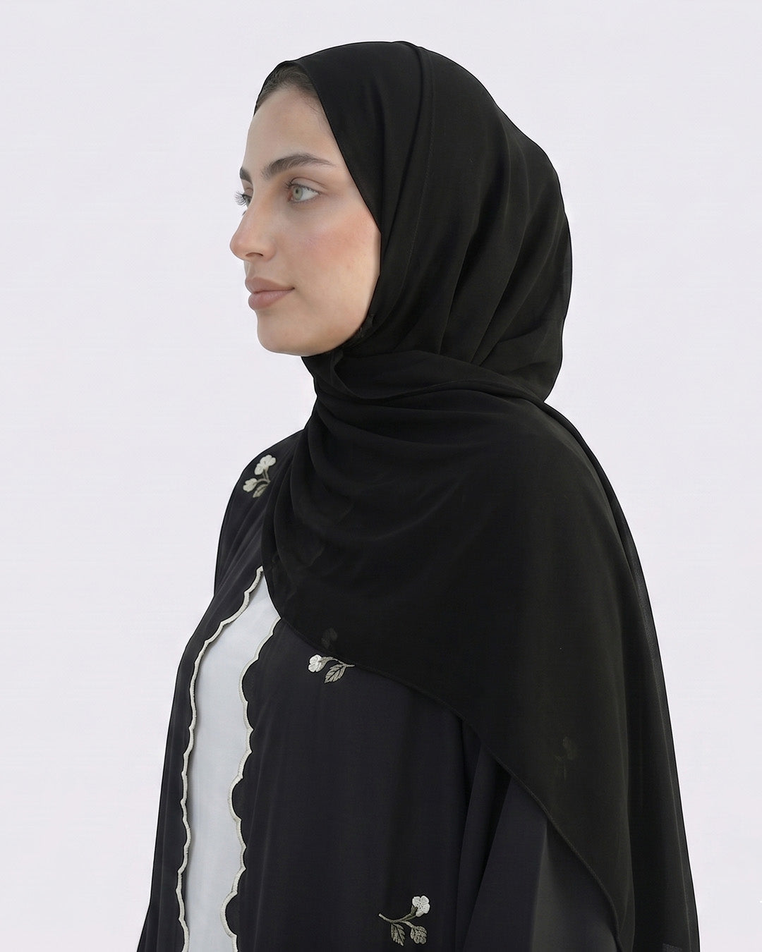 Woman wearing a black hijab against a white background