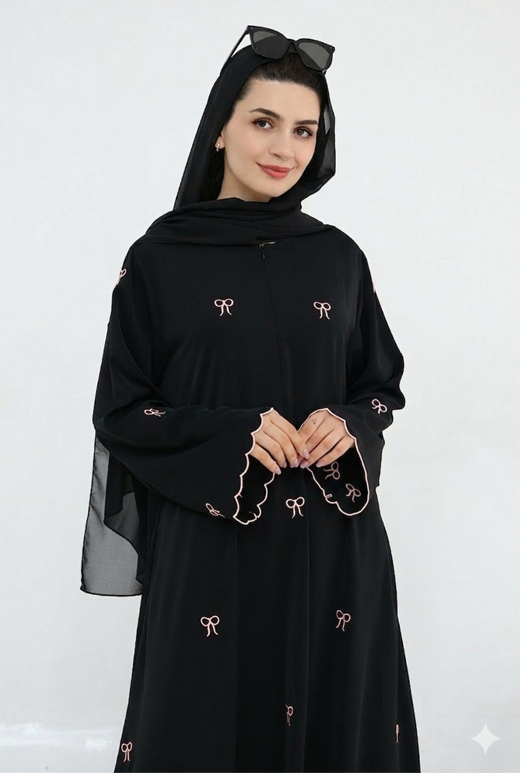 Woman wearing a black abaya with bow details on a white background