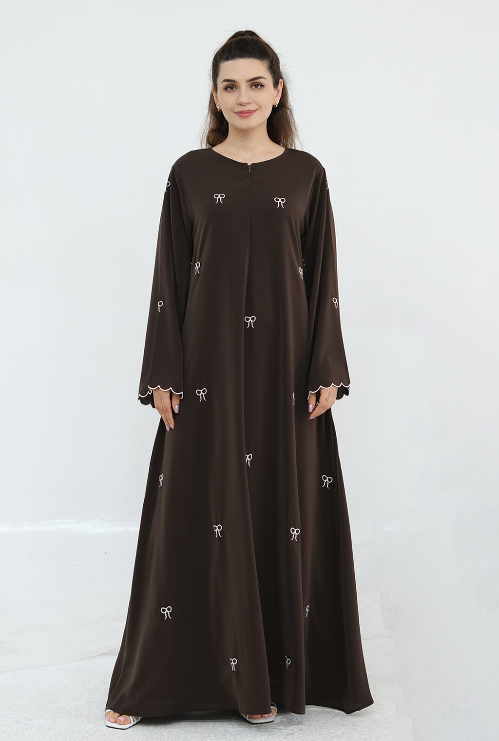 Woman wearing a brown dress with white patterns on a white background